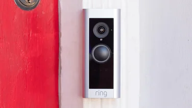 The Ring Video Doorbell Pro 2 pictured on a white door frame with a red painted door to the left