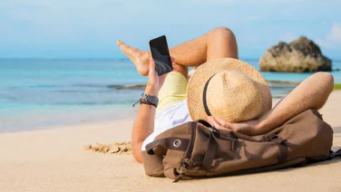 Man on beach looking at smartphone