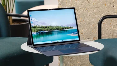 The Dell XPS 13 2-in-1 (2022) facing to the right with keyboard stand on a small white table in an office setting