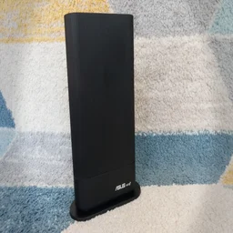 Asus RT-AX59U pictured from the front on a blue, grey and yellow patterend rug
