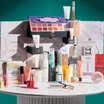 best beauty advent calendar-Glossybox calendar filled with skincare and makeup products unboxed on a white table with a dark green background