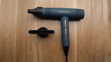 mdlondon BLOW hair dryer in blue on a wooden background, with concentrator nozzle attachments