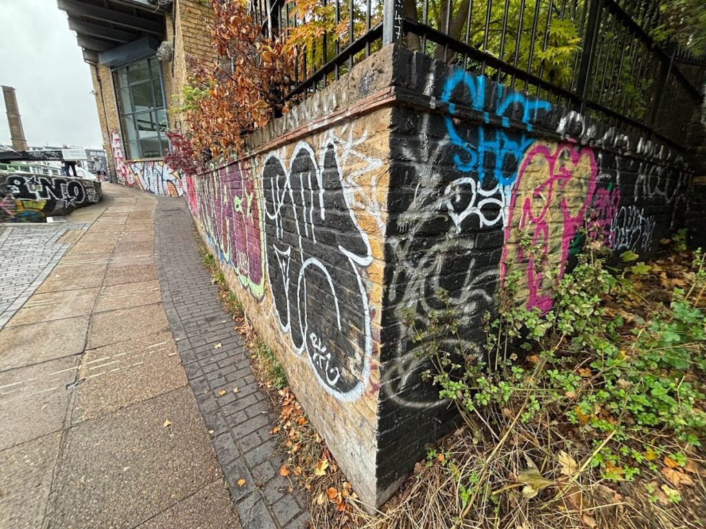 The iPhone 15 Plus captures an image of graffiti on a brick wall at Regent's Canal