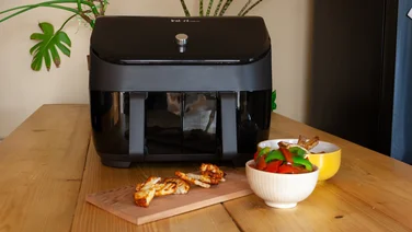 An instant vortex air fryer with cooked chicken and peppers