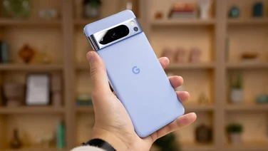 Rear of Google Pixel 8 Pro in hand against bookcase background