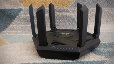 The Asus RT-AXE7800 pictured on a grey, blue and yellow rug