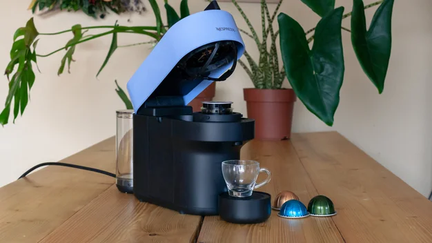 A coffee pod machine with cup and a selection of coffee pods