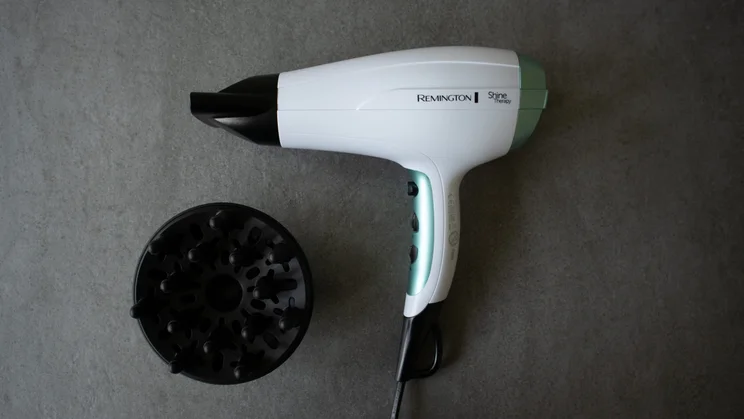 remington shine therapy hair dryer with black diffuser and concentrator nozzle photographed on a grey slate table