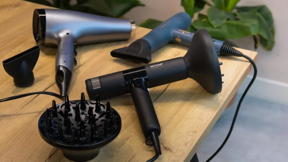 best hair dryer an image of three hair dryers on a wooden table with diffuser attachments and concentrator nozzles
