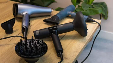 best hair dryer an image of three hair dryers on a wooden table with diffuser attachments and concentrator nozzles