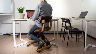 Example of a man at an office desk sitting in a kneeling office chair