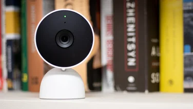 Best home security camera. The Nest Cam Indoor standing in front of books