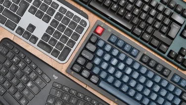 Four keyboards arranged on the diagonal on a wood surface
