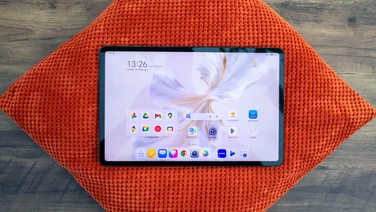 Honor Pad 9, display on, sitting on an orange cushion on a desk