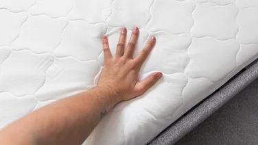 A hand pressing down on a memory foam mattress