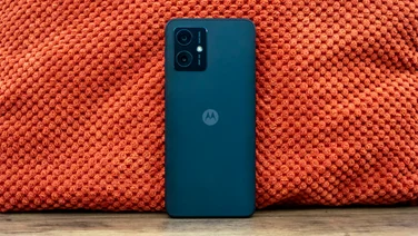 Motorola Moto G54 5G on a desk, leaning up against an orange cushion, rear view