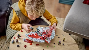 best new lego star wars sets header young boy building a Lego star ship on a wooden table