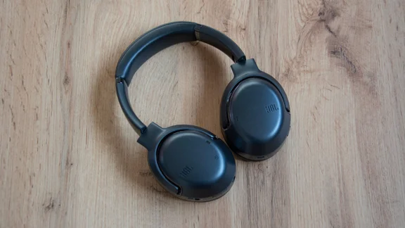 Aerial shot of the JBL Tour One M2 headphones on wooden floor background with their earcups facing the ground