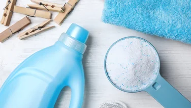 blue detergent bottle with powdered detergent, a blue towel and wooden pegs