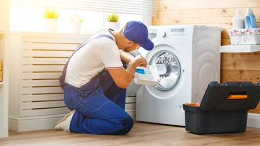 A plumber works on repairing a washing machine