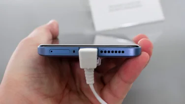 How to keep your phone battery healthy - featured. Xiaomi 14 Ultra bottom edge, in hand, grey bench in the background