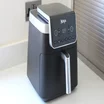 A Ninja Air Fryer Max Pro 6.2l AF180UK sitting on a kitchen counter top, with the display panel showing a timer countdown