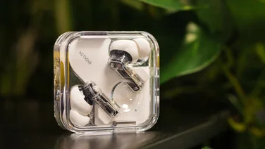 An image of the Nothing Ear (2024) true wireless earbuds in their charging case with a plant in the background