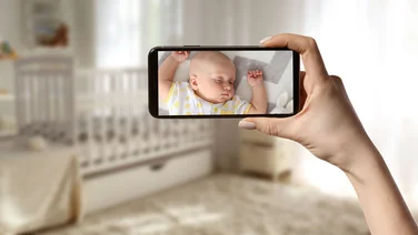 Are baby monitors really worth it header mum monitoring her baby on her mobile phone