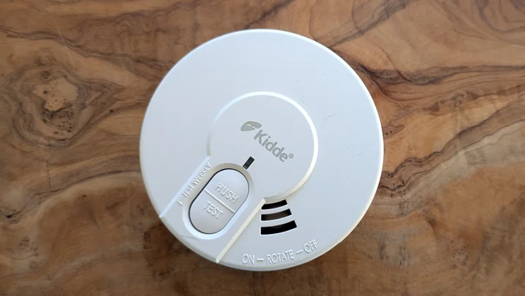 The Kidde DY29 smoke alarm, pictured on a wood surface from above