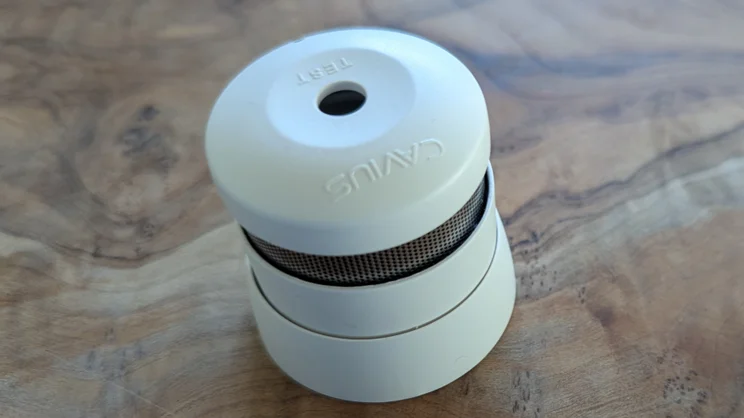 The Kidde K2007 mini smoke alarm pictured on a wood surface