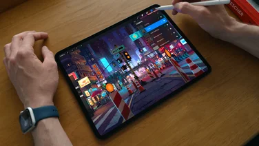 M4 iPad Pro on a table, person's hands in view, editing an intricate drawing of a street at night