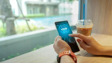 Close up of Woman using a phone with eSIM technology in a cafe.