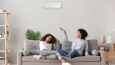 family sitting on sofa turning on air conditioning - how to cool down a room