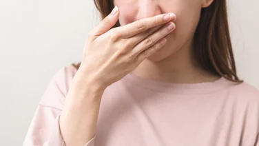 A close up of a woman covering her mouth with her hand