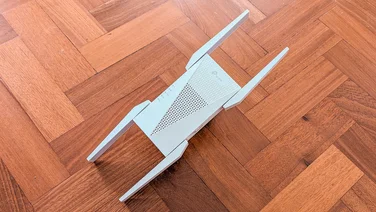 The TP-Link RE815XE wireless extender pictured on a parquet floor