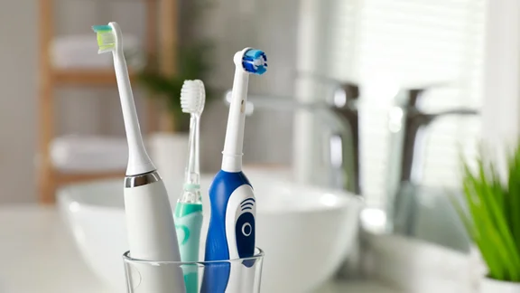 electric toothbrushes in holder on bathroom sink - why are electric toothbrushes so expensive