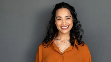 woman smiling with white teeth on grey background - how to naturally whiten teeth