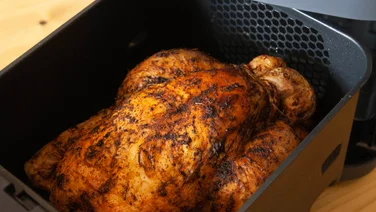Air fryers are replacing UK takeaway - featured. Close up of a cooked chicken in an air fryer basket