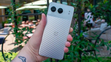 OnePlus Nord 4, in hand, rear view, in front of metal railings