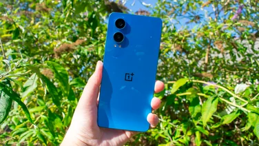 OnePlus Nord CE 4 Lite in hand, rear view, in front of some trees
