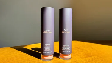 An image of the Dyson Chitosan pre-styling cream and post-styling serum on a wooden surface