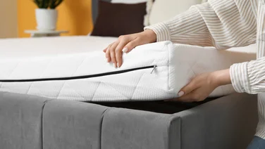 A mattress being handled on a bed frame