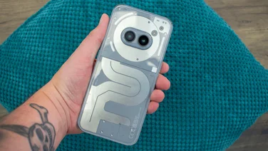 Nothing Phone (2a) Plus in hand, rear view, in front of a blue cushion