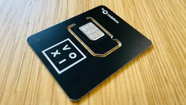A black Voxi SIM card on a wooden table