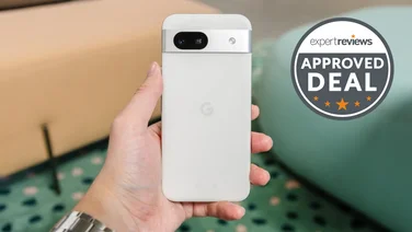 Google Pixel 8a in hand, rear view, with low sofas in the background