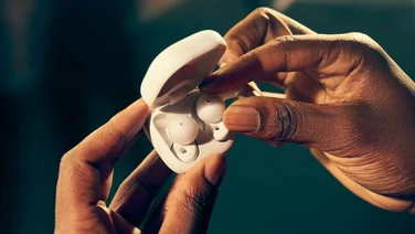 Hands holding the Sony LinkBuds Open in their case, removing an earbud