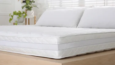 A white mattress in a brightly lit bedroom