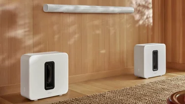 Image displaying the Sonos Arc Ultra soundbar hanging on a wall above a pair of Sonos Sub 4 subwoofers