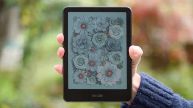 Amazon Kindle Colorsoft Signature Edition pictured face on in the hand against a green blurry background