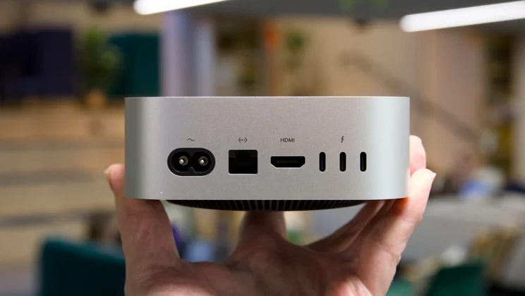 The rear of the Mac mini (2025) held in a hand